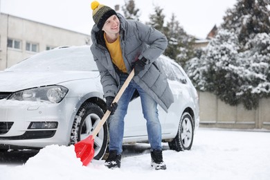 Photo of Man removing snow with shovel near car outdoors