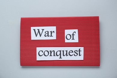 Photo of Red paper with words War Of Conquest on white background, top view