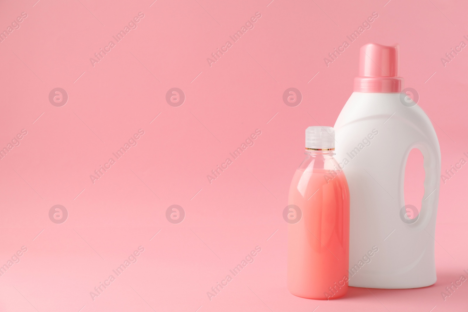 Photo of Bottles of laundry detergents on pink background. Space for text