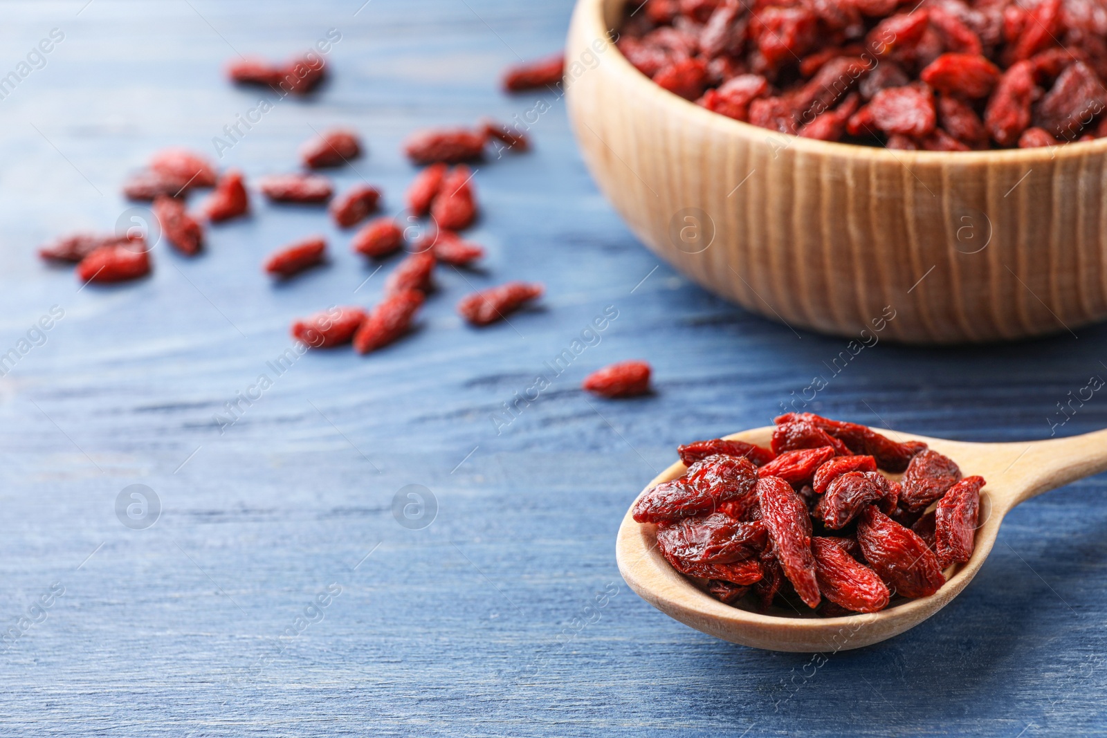 Photo of Dry goji berries on blue wooden table, closeup