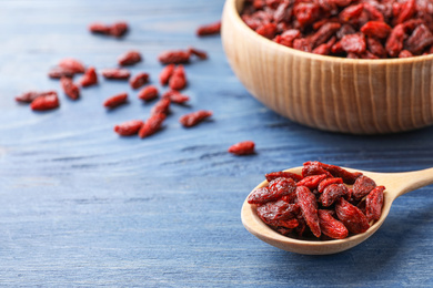 Photo of Dry goji berries on blue wooden table, closeup