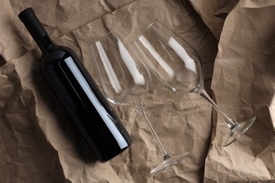 Photo of Stylish presentation of delicious red wine in bottle and glasses on paper background, top view