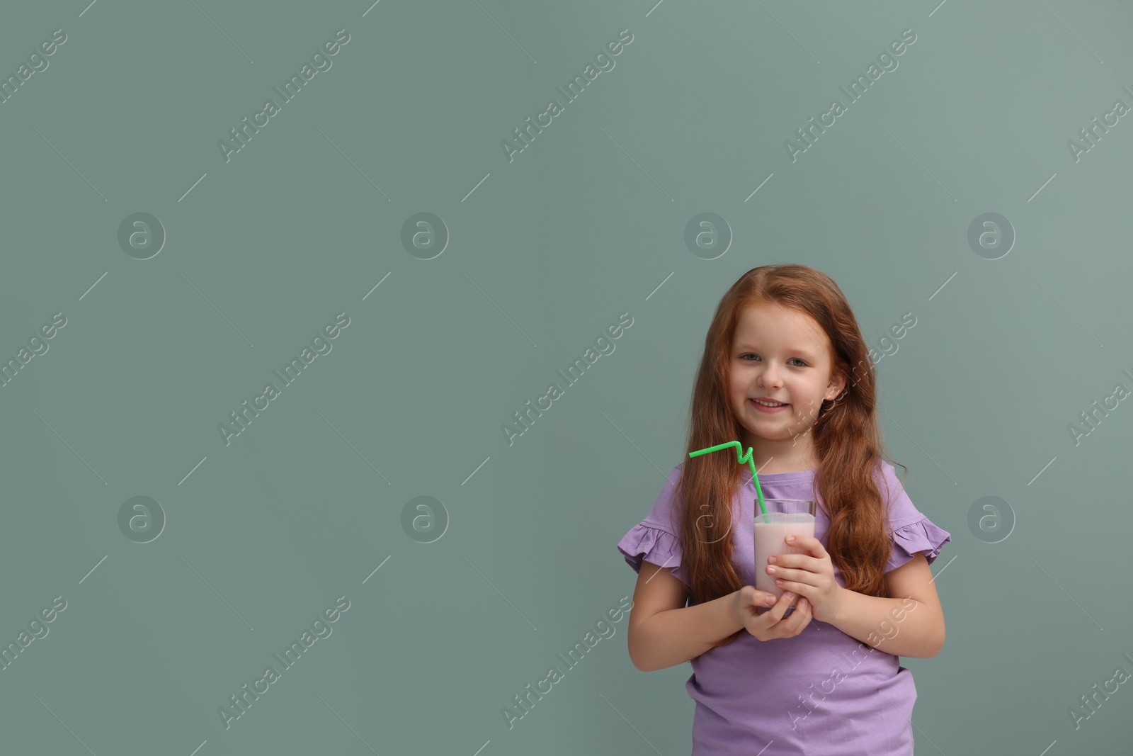 Photo of Little girl with glass of delicious milk shake on color background