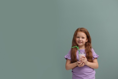 Little girl with glass of delicious milk shake on color background