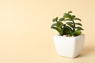 Photo of Beautiful artificial plant in flower pot on beige background, space for text