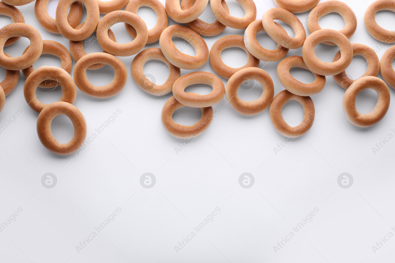 Photo of Many tasty dry bagels (sushki) on white background, flat lay. Space for text