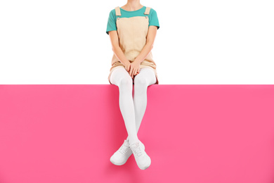 Woman wearing white tights and stylish shoes sitting on color background, closeup