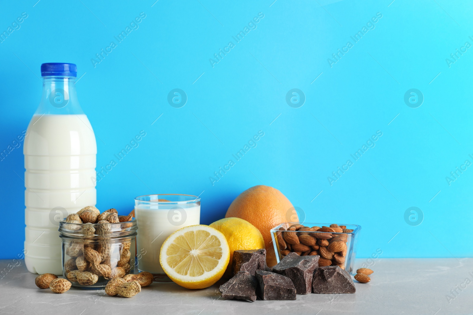 Photo of Different products on stone table against light blue background, space for text. Food allergy concept