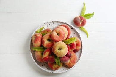 Photo of Fresh ripe donut peaches on white wooden table, flat lay