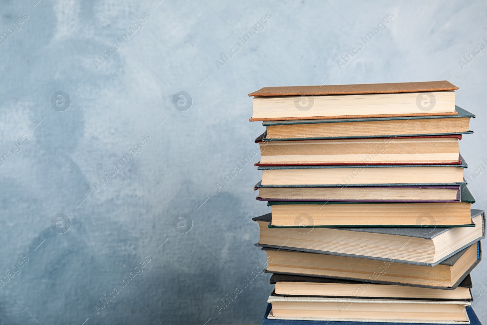 Photo of Stack of hardcover books on light blue background. Space for text