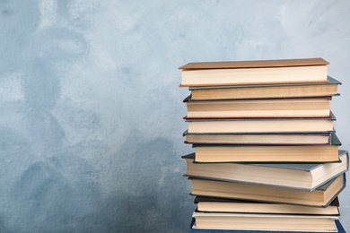 Stack of hardcover books on light blue background. Space for text