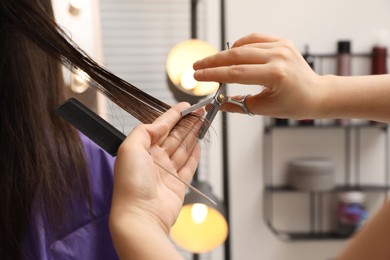 Photo of Professional stylist cutting client's hair in salon, closeup