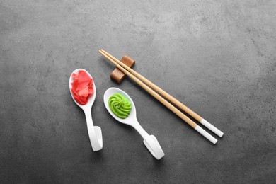 Photo of Swirl of wasabi paste, pickled ginger and chopsticks on grey table, flat lay