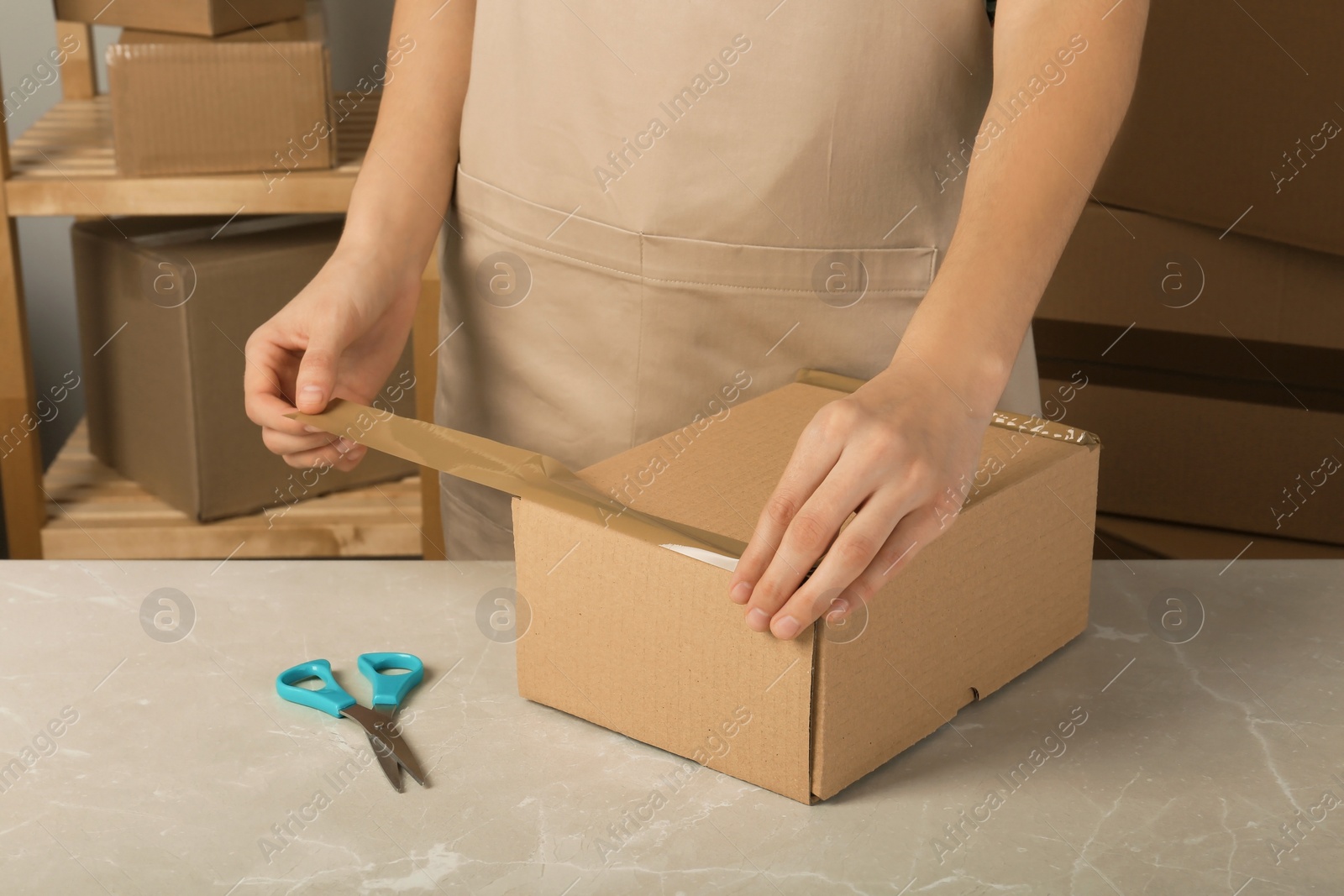 Photo of Woman packing box at table, closeup. Space for design