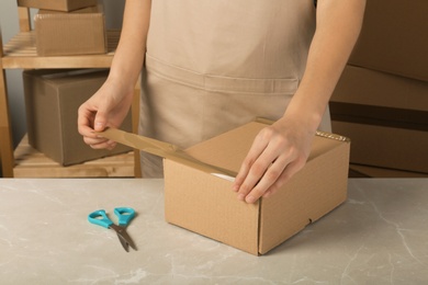 Photo of Woman packing box at table, closeup. Space for design