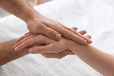 Photo of Woman receiving hand massage on soft towel, closeup