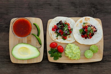 Photo of Delicious tacos and ingredients on wooden table, top view. Mexican food