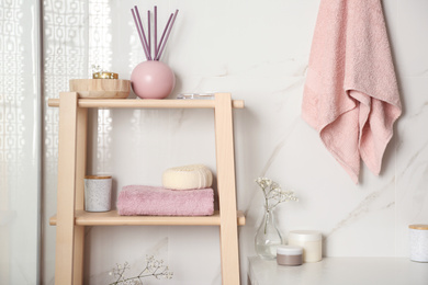 Shelving unit with towel and decorative elements in bathroom interior