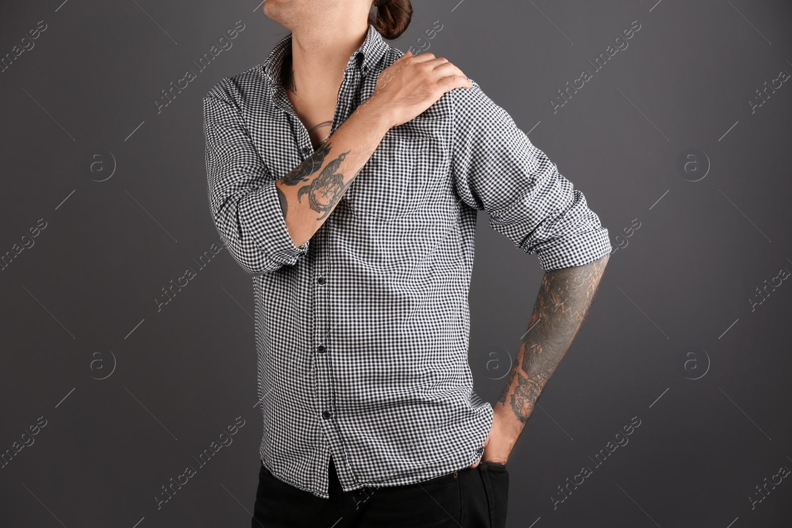 Photo of Young man with stylish tattoos on grey background