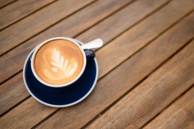 Photo of Cup of aromatic coffee on wooden table, above view. Space for text