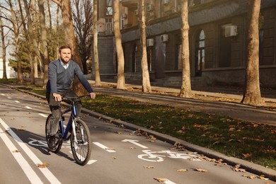 Photo of Happy handsome man riding bicycle on lane in city