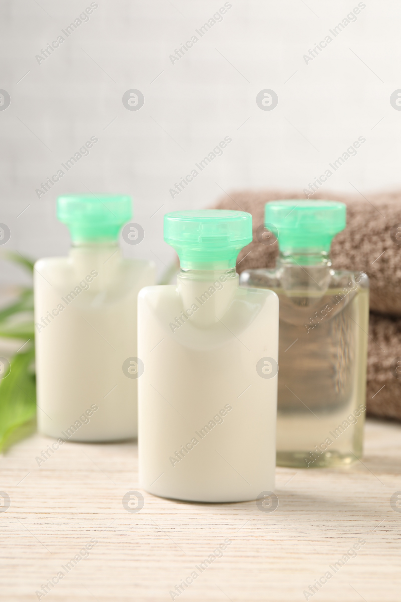 Photo of Mini bottles of cosmetic products on white wooden table