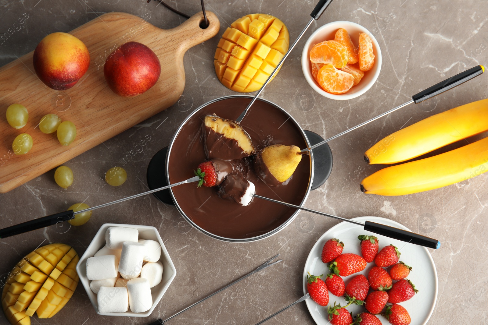 Photo of Flat lay composition with chocolate fondue in pot and fruits on gray background