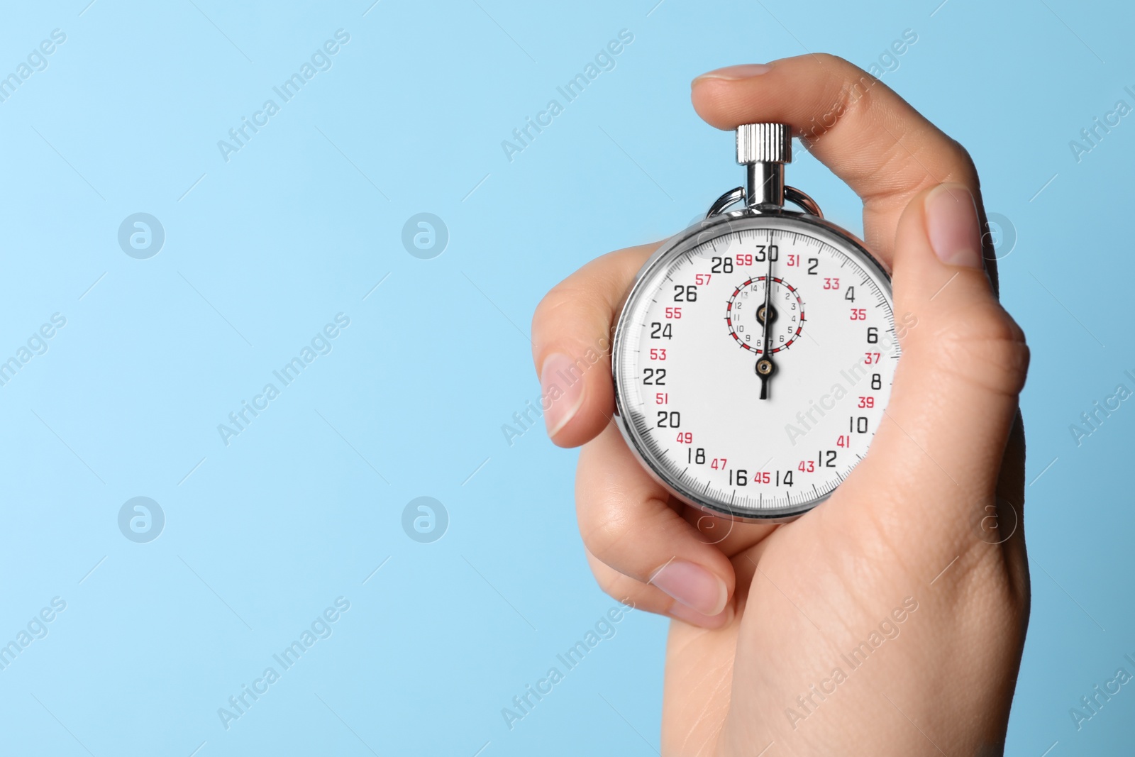 Photo of Woman holding vintage timer on light blue background, closeup. Space for text