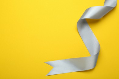 Beautiful ribbon on yellow background, top view. Space for text