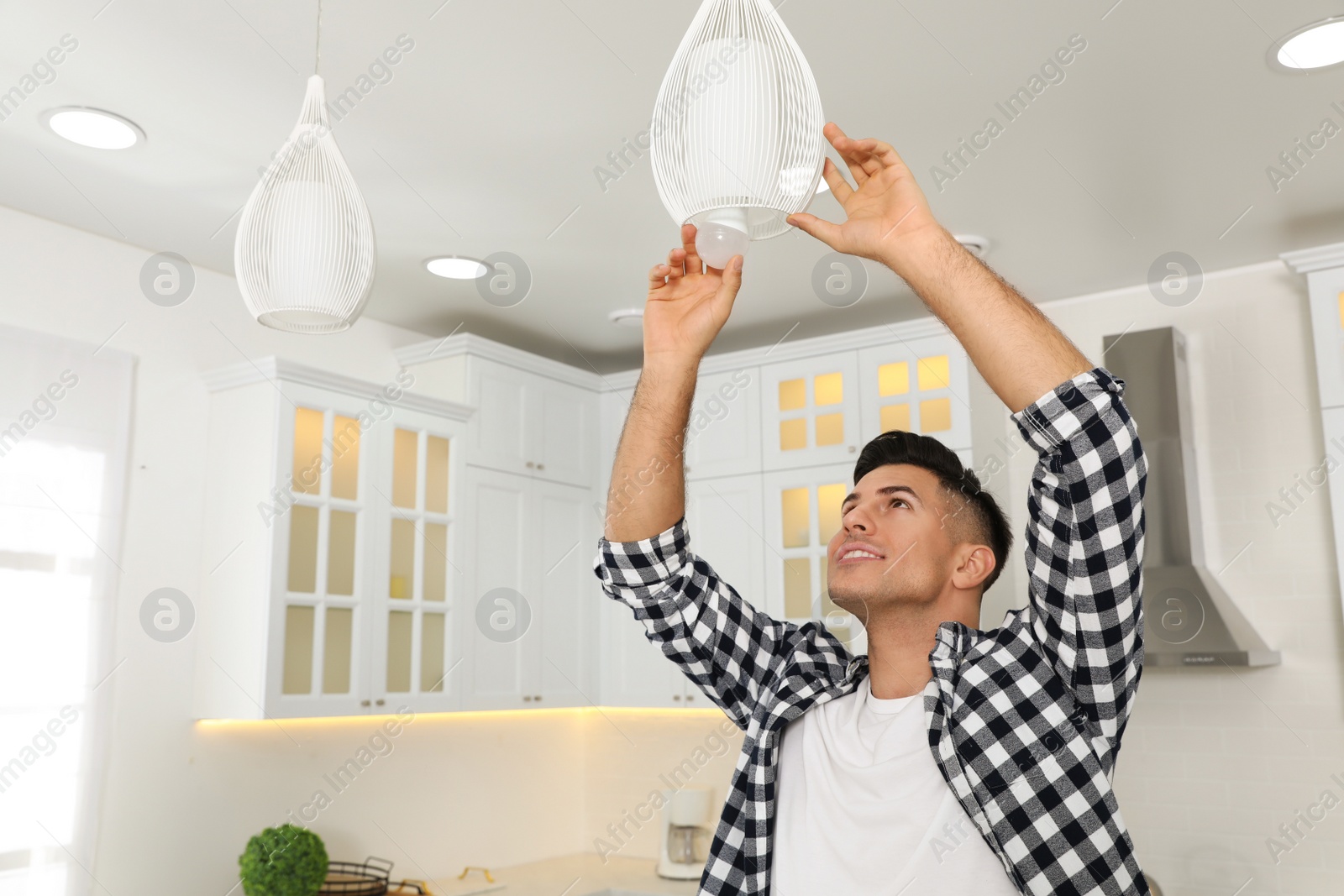 Photo of Man changing light bulb in lamp at home. Space for text