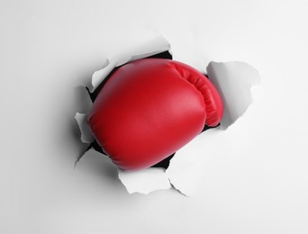 Photo of Man breaking through white paper with boxing glove, closeup