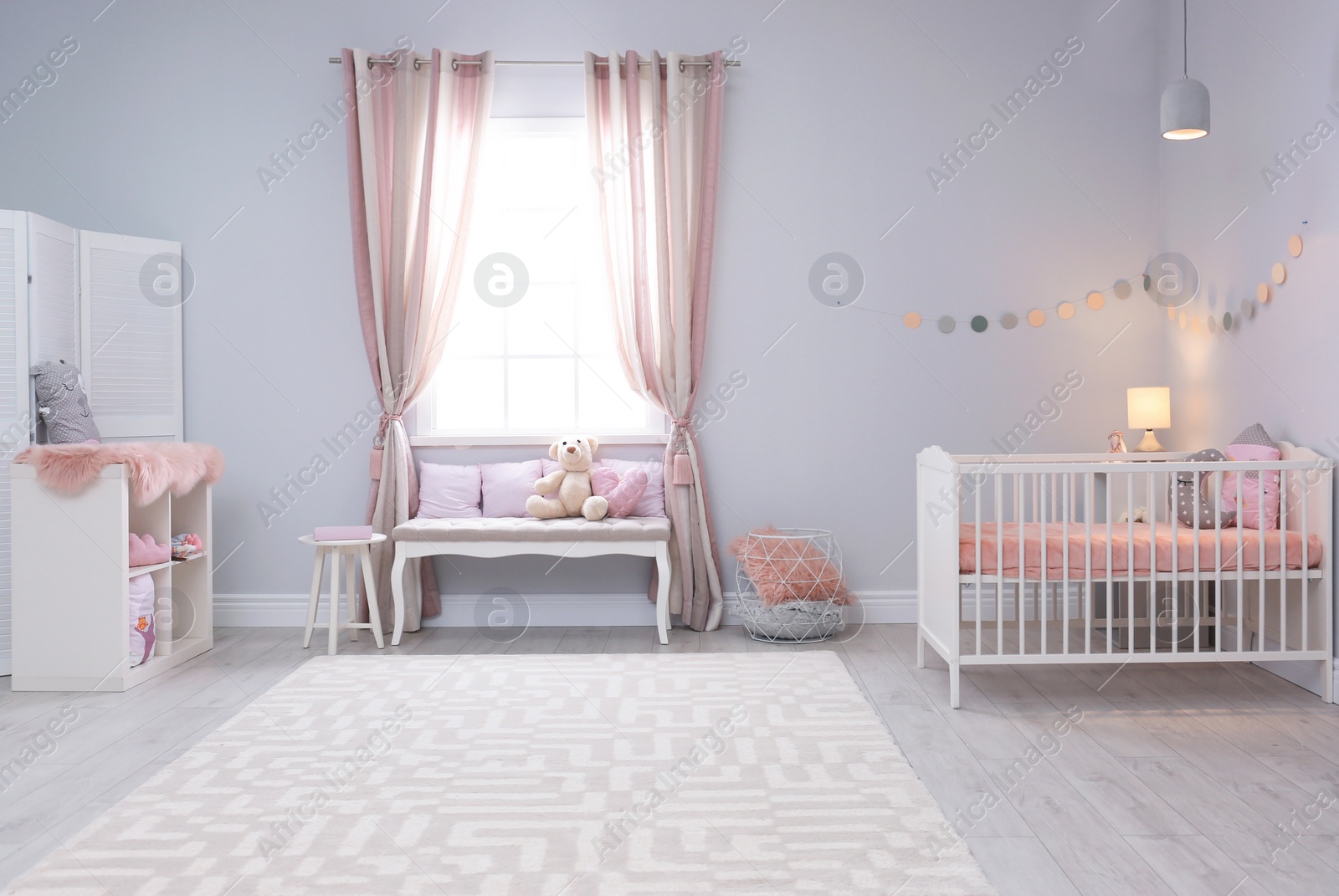 Photo of Baby room interior with comfortable crib and indoor bench