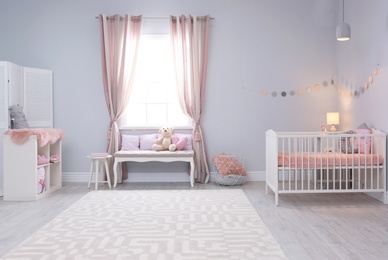 Photo of Baby room interior with comfortable crib and indoor bench