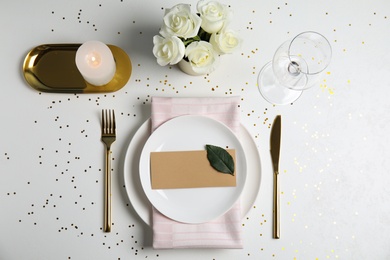 Elegant festive table setting with blank card on white background, flat lay