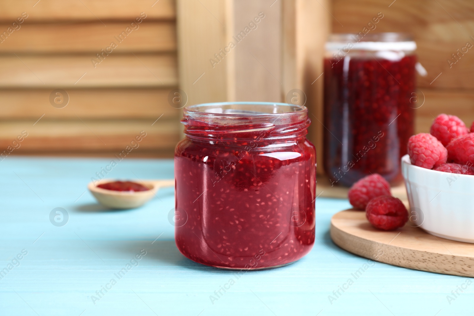 Photo of Delicious raspberry jam on light blue wooden table