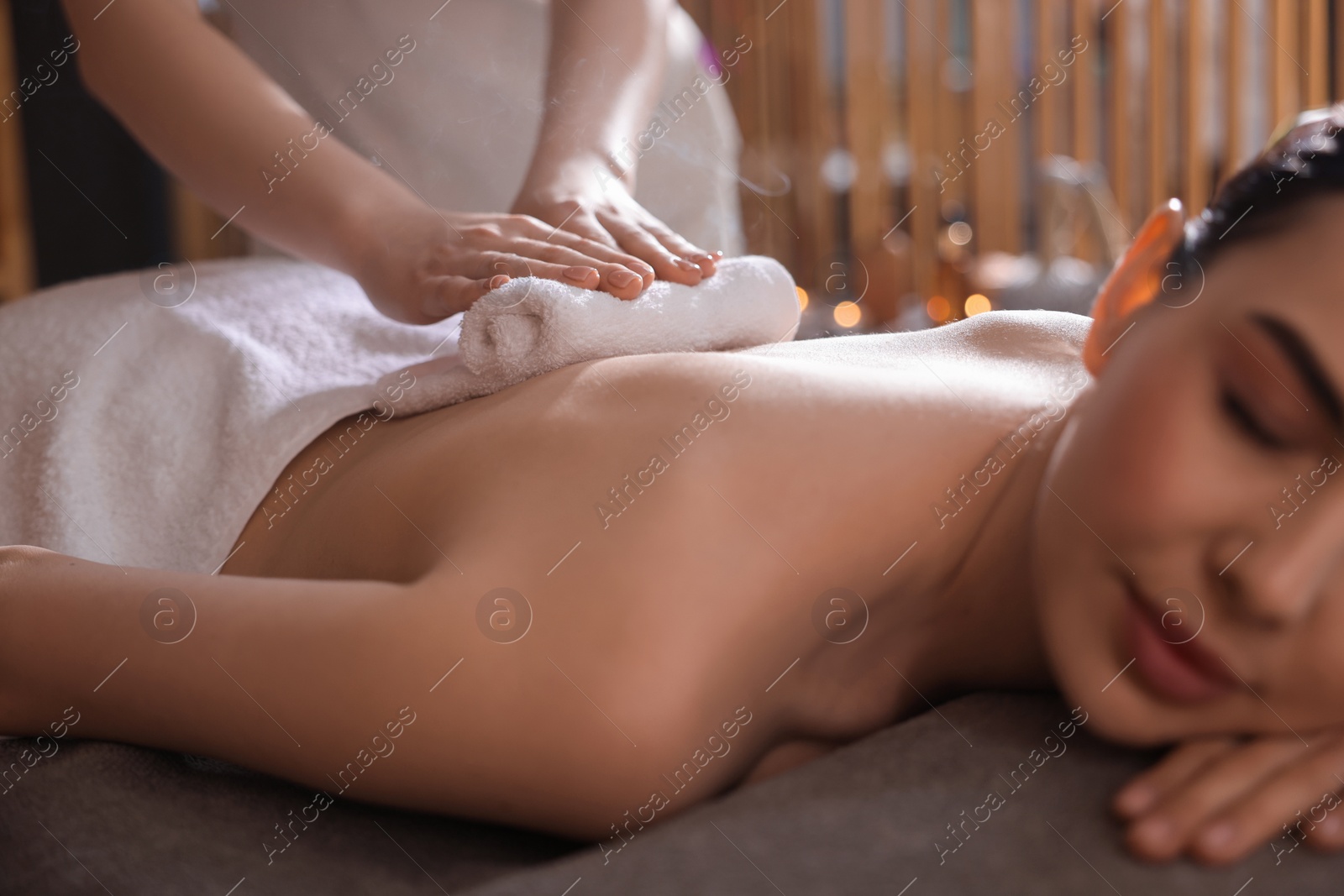 Photo of Spa therapy. Beautiful young woman lying on table during hot towel massage in salon, closeup