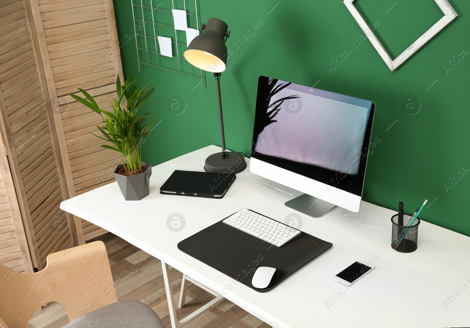 Photo of Stylish workplace with modern computer near color wall. Space for text