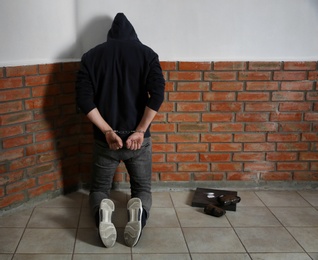 Photo of Male drug dealer in handcuffs near brick wall. Space for text