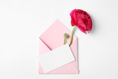 Photo of Envelope with card and beautiful ranunculus flower on white background, top view. Space for text