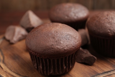 Photo of Delicious chocolate cupcakes on wooden board, closeup
