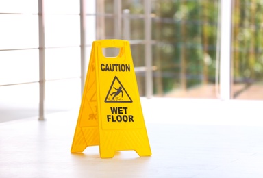 Photo of Safety sign with phrase Caution wet floor, indoors. Cleaning service