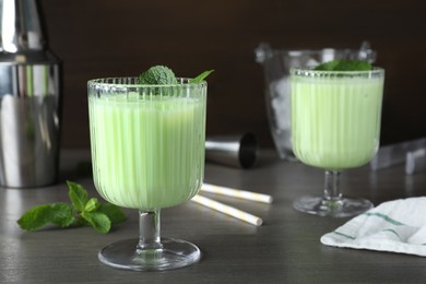 Photo of Delicious mint liqueur with green leaves on grey wooden table. Space for text