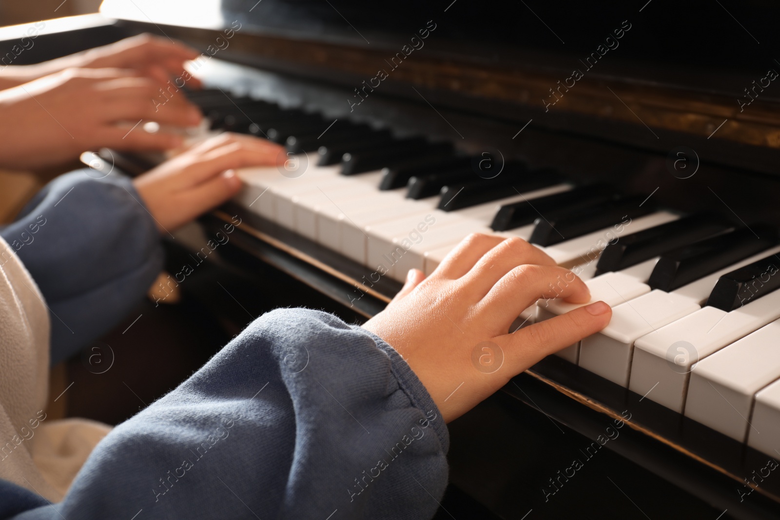 Photo of Young woman with child playing piano, closeup. Music lesson