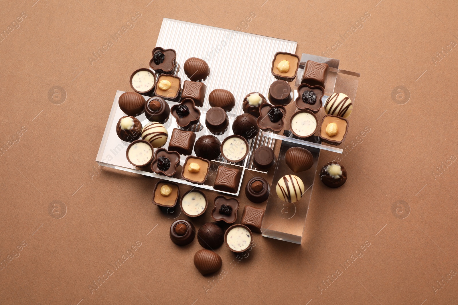 Photo of Heart made with delicious chocolate candies on brown background, top view