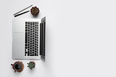 Modern laptop, houseplants and cup of coffee on white table, flat lay. Space for text