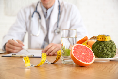 Photo of Healthy products, measuring tape and blurred nutritionist on background