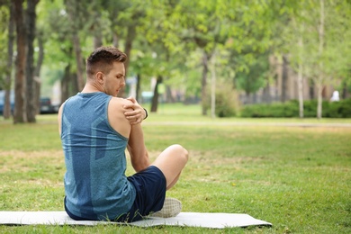 Photo of Male athlete suffering from shoulder pain during training outdoors