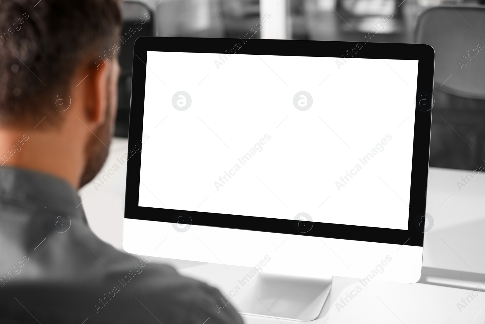 Photo of Man using modern computer at white desk in office, back view. Mockup for design