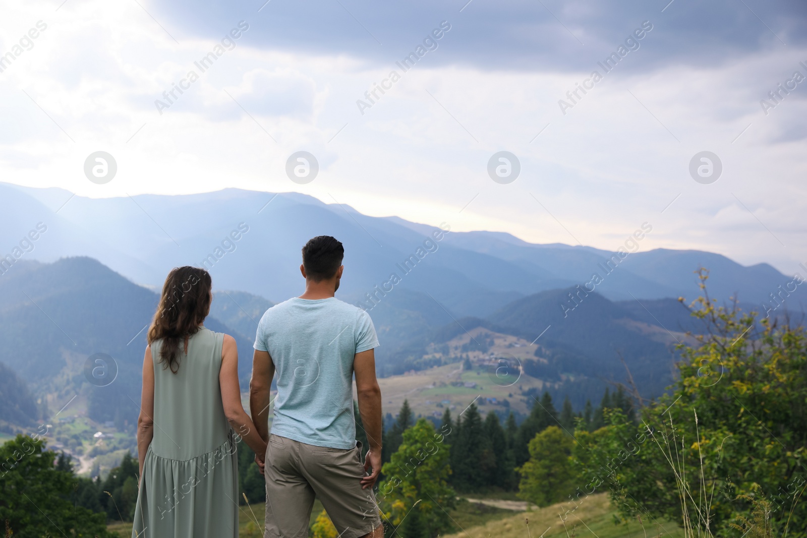 Photo of Couple enjoying beautiful mountain landscape, back view. Space for text