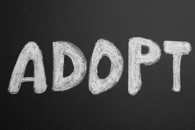 Word ADOPT written on blackboard, top view